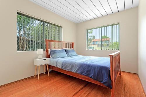 a bedroom with a bed and two windows at Poseidons Hideaway by Experience Jervis Bay in Vincentia