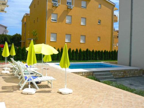 um grupo de guarda-sóis e cadeiras amarelas junto a uma piscina em Family friendly apartments with a swimming pool Kozino, Zadar - 18128 em Kožino