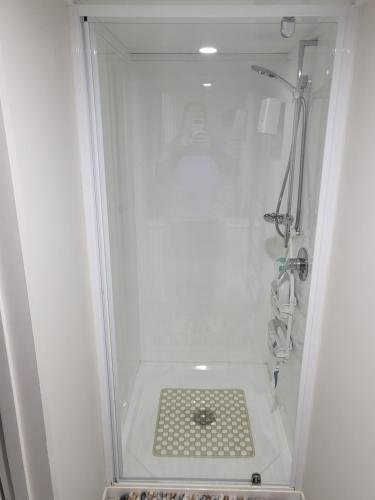 a white shower with a drain in a bathroom at BARNES STREET BNB in Timaru