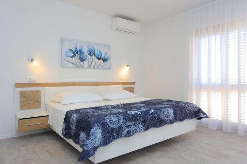 a white bedroom with a bed and a window at Apartments with a swimming pool Zrnovnica, Split - 18147 in Žrnovnica