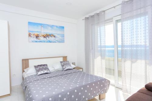 a bedroom with a bed and a large window at Family friendly apartments with a swimming pool Zivogosce - Porat, Makarska - 18150 in Živogošće