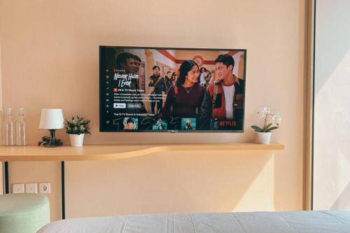 a flat screen tv sitting on top of a wall at Cozy Studio Suite in Taman Anggrek Residences in Jakarta