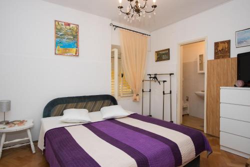 ein Schlafzimmer mit einem Bett mit einer lila und weiß gestreiften Decke in der Unterkunft Apartments by the sea Krapanj, Sibenik - 18180 in Šibenik