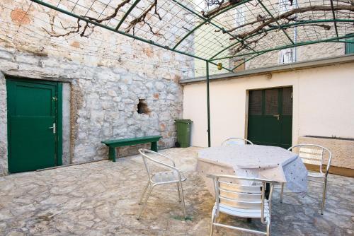 eine Terrasse mit einem Tisch, Stühlen und einer Steinmauer in der Unterkunft Apartments by the sea Krapanj, Sibenik - 18180 in Šibenik