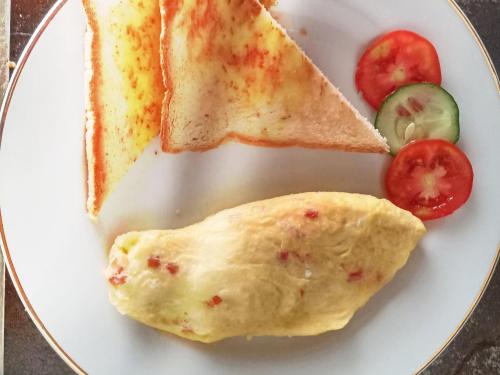 a plate of breakfast food with an omelet and toast at THE OWN PENIDA COTTAGE & SPA in Nusa Penida