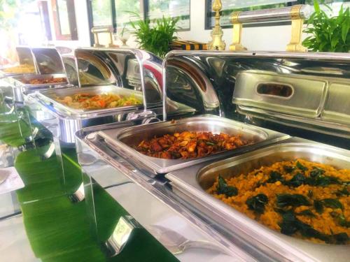 a buffet with several trays of food on a table at Flower Garden Eco Village in Sigiriya