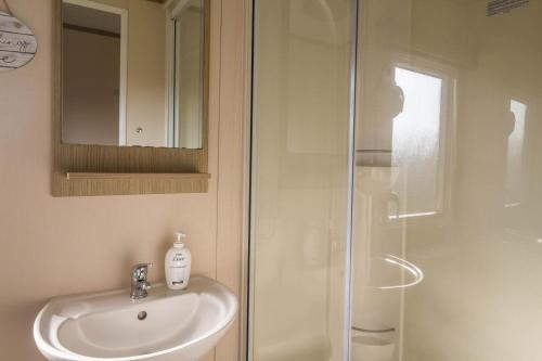 a bathroom with a sink and a shower at Caravan With Decking At Coopers Beach Holiday Park Ref 49012cw in East Mersea