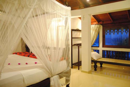 a bedroom with a bed with white mosquito netting at La Veranda Di Serena in Unawatuna