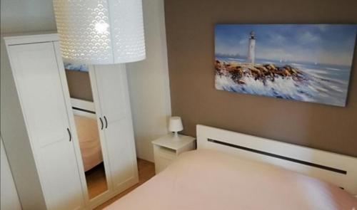 una camera con letto bianco e foto di un faro di Apartments by the sea Kustici, Pag - 18248 a Zubovići