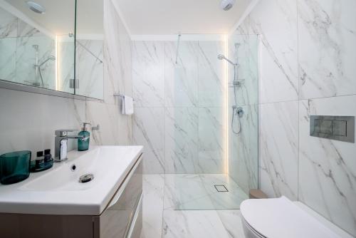 a white bathroom with a shower and a sink at Apartament Prestige Centrum in Bielsko-Biała