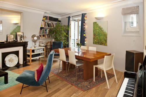 - une salle à manger avec une table, des chaises et un piano dans l'établissement Chic Saint Germain Apartment, à Paris
