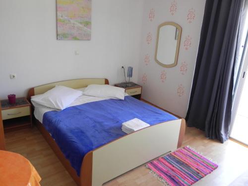 ein Schlafzimmer mit einem Bett mit einer blauen Decke und einem Spiegel in der Unterkunft Apartments by the sea Kampor, Rab - 18268 in Rab