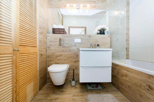 a bathroom with a toilet and a sink and a tub at Carmel Rentyear Apartments in Gdańsk