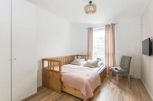 a bedroom with a bed and a window and a chair at Carmel Rentyear Apartments in Gdańsk
