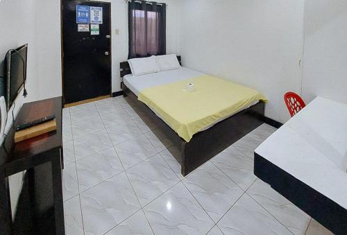 a room with a bed with a yellow sheet on it at RedDoorz Buena's Pension in Puerto Princesa City