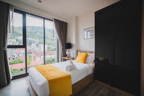 a bedroom with a bed and a large window at The deck patong 5 Star Apartment 巴东The Deck无边际海景泳池酒店 in Patong Beach