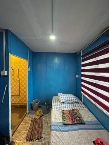 Zimmer mit einem Bett und einer blauen Wand in der Unterkunft Z&Z Budget Room in Kampung Kuala Besut