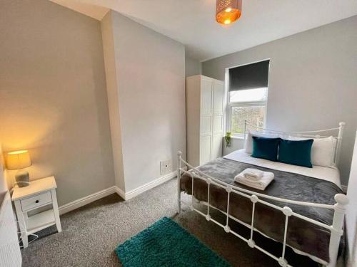 a bedroom with a bed with blue pillows and a window at URBAN CITY SUITES 4 bed house, garden, Ideal for Contractors&Families in Quinton