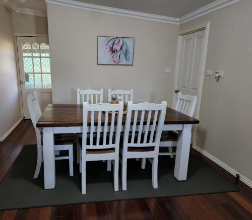 a dining room with a table and white chairs at Yvonnes Rest Holiday Home in Bridgetown