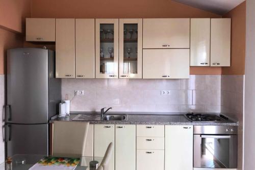 cocina con armarios blancos y nevera de acero inoxidable en Apartments with a parking space Katuni, Zagora - 18344, en Šestanovac