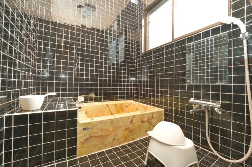 a black tiled bathroom with a tub and a toilet at Toya Blue in Lake Toya