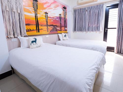 two white beds in a room with a painting on the wall at Jin Da Paint B&B in Jinning