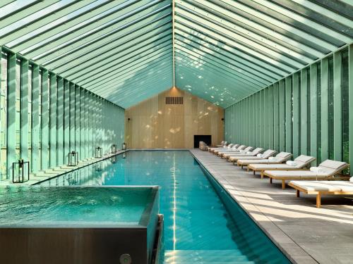 a large swimming pool with chairs and a swimming pool at Botanic Sanctuary Antwerp - The Leading Hotels of the World in Antwerp