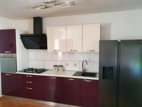 une cuisine avec des placards violets et un réfrigérateur noir. dans l'établissement Apartments with a parking space Bol, Brac - 18358, à Bol