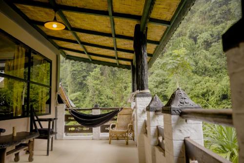 a room with a hammock and a view of the forest at Jungle Inn Bukit lawang in Bukit Lawang