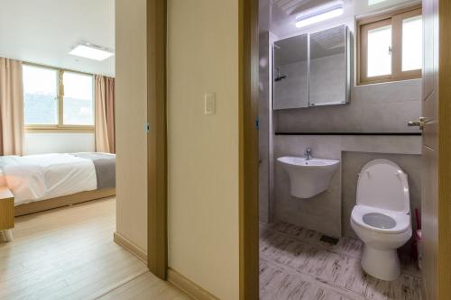 a bathroom with a toilet and a sink and a bed at JS Residence Hotel Okpo in Geoje 