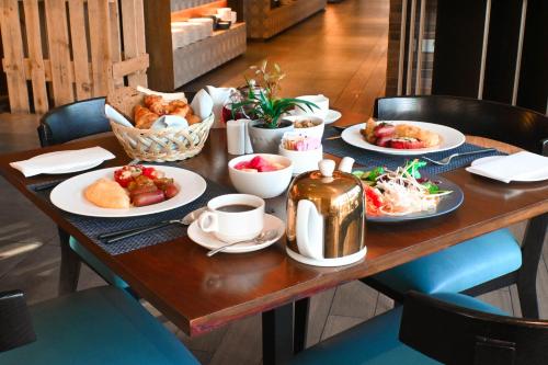 a table with plates of food and cups of coffee at Novotel Dubai Gold District in Dubai
