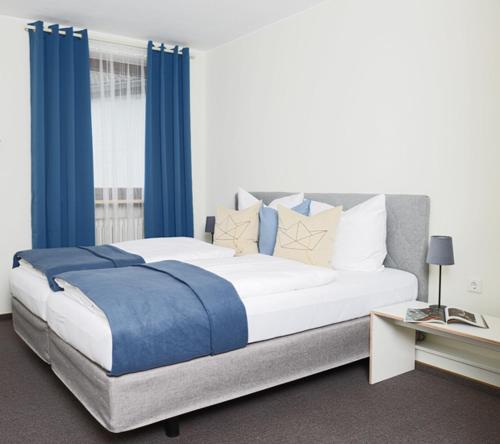 a bedroom with a large bed with blue curtains at Senefelder Hof in Solnhofen