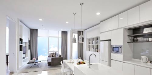 a kitchen with white cabinets and a living room at THE FACE Suites in Kuala Lumpur