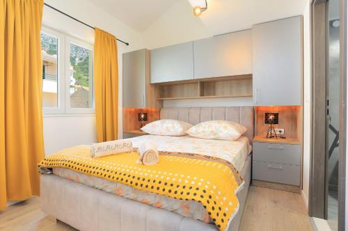 a bedroom with a bed with a yellow blanket on it at Apartments by the sea Igrane, Makarska - 18405 in Igrane