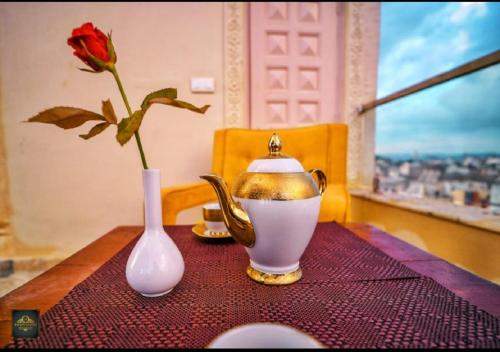 a tea pot and a vase on a table with a rose at Royal Rafahiya Haveli - LAKE FACING in Udaipur
