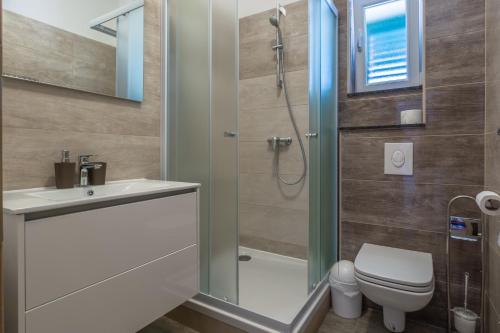łazienka z prysznicem, toaletą i umywalką w obiekcie Apartments by the sea Simuni, Pag - 18386 w mieście Kolan