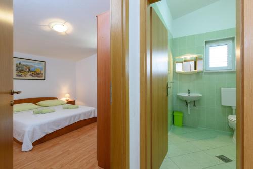 1 dormitorio con 1 cama y baño con lavamanos en Apartments by the sea Seget Vranjica, Trogir - 18229, en Seget Vranjica