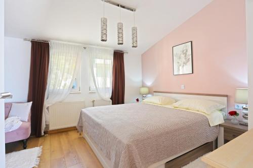 een slaapkamer met een groot bed en een stoel bij Apartments by the sea Seget Donji, Trogir - 18488 in Trogir