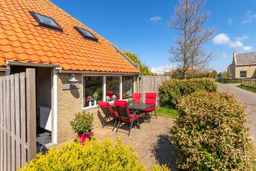 a patio with red chairs and a table at Terschelling Natuurlijk in Kinnum