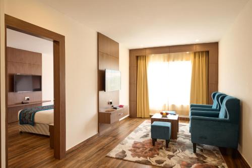 a hotel room with a bed and a blue chair at Renest Haridwar in Haridwār