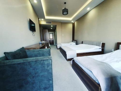 una camera d'albergo con due letti e un divano di Lankaran Olimpiya Hotel a Lankaran