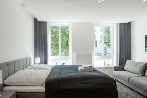 a bedroom with a bed and a couch and windows at LIGHTHOUSE APPARTEMENTS in Warnemünde