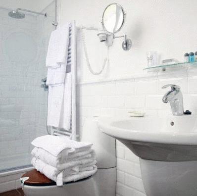 a bathroom with a sink and a mirror and towels at Hotel el Jardín de Eugenia in Ribadesella