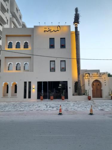 a building with a palm tree in front of it at HÔTEL DE LA MEDINA in Nouakchott