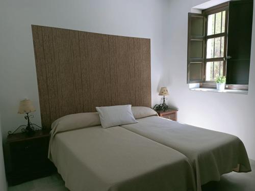 Un dormitorio con una cama grande con dos ventanas. en Estación de Coripe, en Coripe