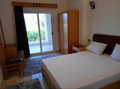 a bedroom with a bed and a window and a chair at Swiss Royal DAHAB in Dahab