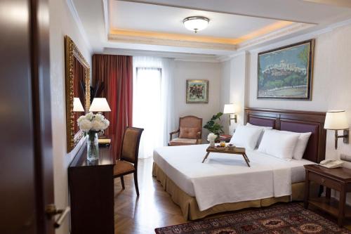 um quarto de hotel com uma cama, uma secretária e uma cadeira em Electra Palace Athens em Atenas