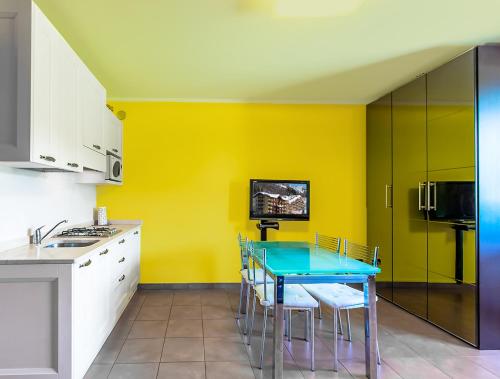 a kitchen with a blue table and yellow walls at Capanna in Prato Nevoso