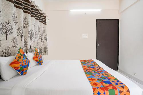 um quarto com uma cama branca e almofadas coloridas em FabHotel Vardhan House II em Dāpuri