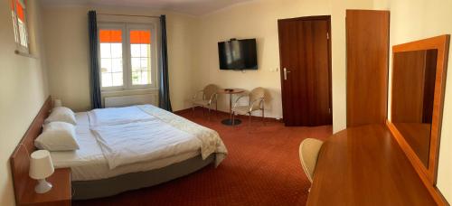 a bedroom with a bed and a television and a table at Hotel Gryf in Kościerzyna